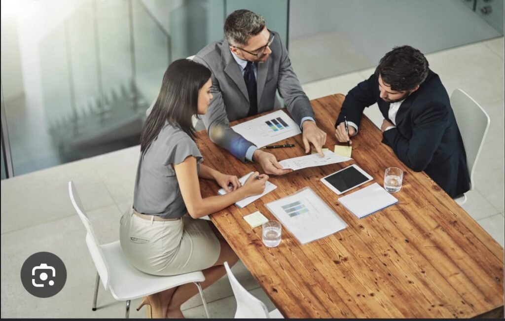Three business professionals discussing digital marketing strategies, reviewing documents and charts during a business meeting